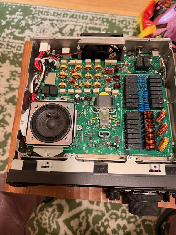 An HF radio transceiver with its cover removed, showing circuit boards, relays, and hand-wound coils.